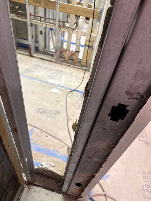 Rusted, mold-stained wall stud, and a cleaned stud wall with a bare tile floor.